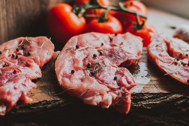 Pedaços de bife de carne de porco crua com especiarias e ervas Alecrim, tomilho, manjericão, sal e pimenta