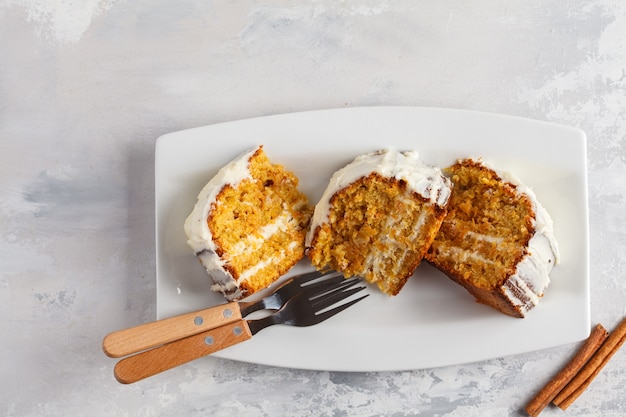 Pedaços de bolo de cenoura caseiro vegan com creme branco em um prato branco, vista superior. conceito de sobremesa festiva.