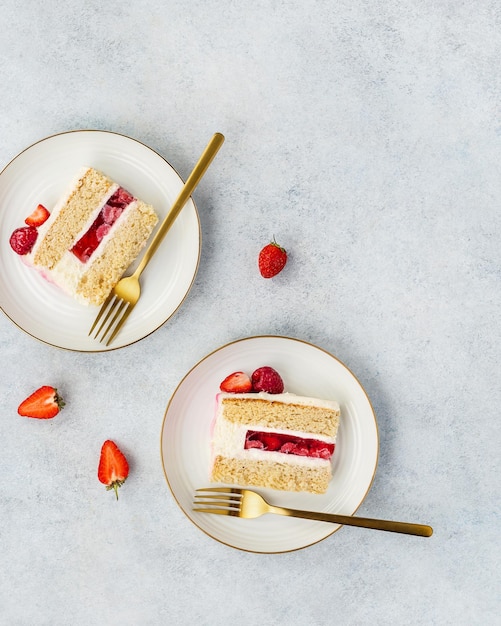 Pedaços de bolo de morango com morangos frescos e creme de leite em um fundo branco