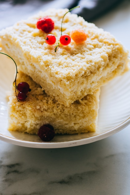 Pedaços de bolo de queijo cottage com um crumble decorado com framboesas e groselhas