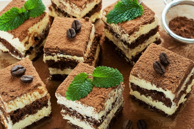 Pedaços de bolo tiramisu com creme delicado, grãos de café e folhas de hortelã.