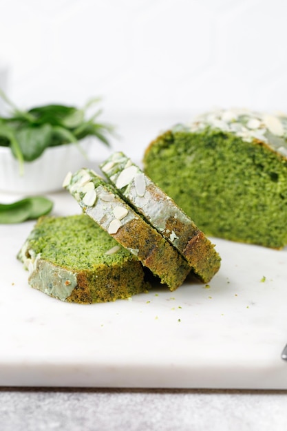 Pedaços de bolo verde esponja com espinafre Torta verde com amêndoas lascadas cortadas na placa de mármore