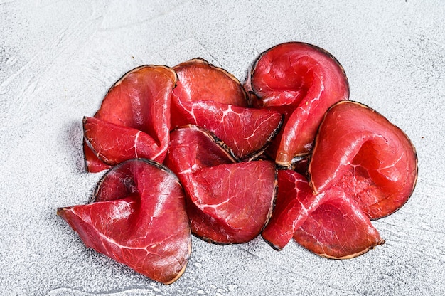 Pedaços de bresaola defumada, antepastos italianos. Fundo branco. Vista do topo.