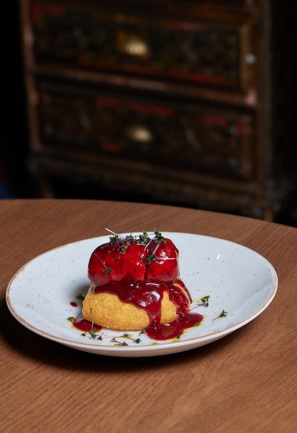 Pedaços de carne de pato assado estão em um prato branco sob a carne é um molho doce vermelho decorado com ve