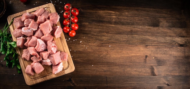 Pedaços de carne de porco crua em uma tábua com salsa e tomate