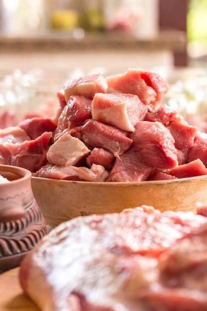 Pedaços de carne picada em uma tigela de cerâmica, perto de filetes e sal. vertical. espaço para texto. carne estufada e receita de churrasco