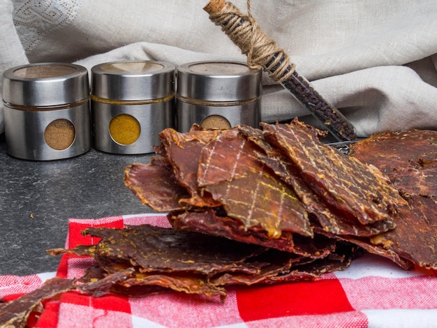 Pedaços de carne seca fatias desidratadas em especiarias na toalha de cozinha