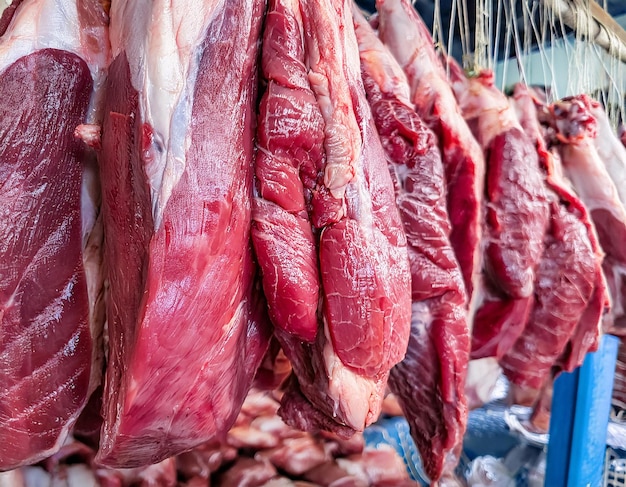 pedaços de carne vermelha crua pendurados numa loja de mercado tradicional