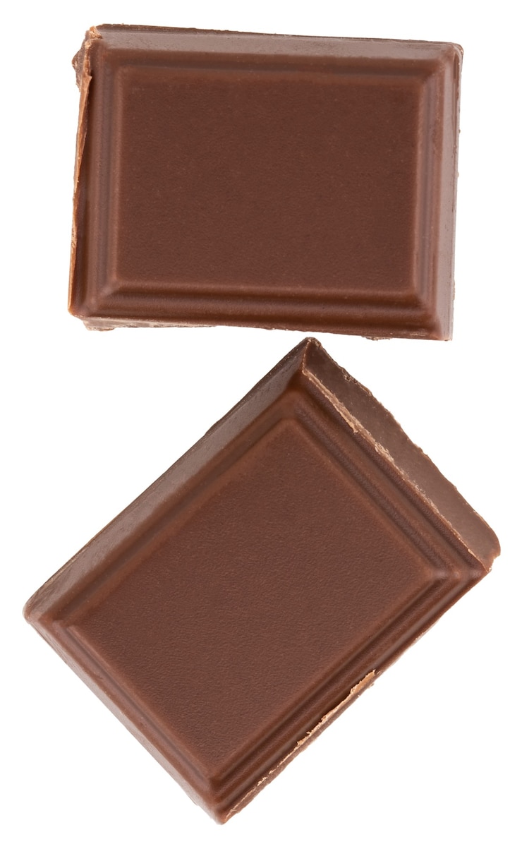 Foto pedaços de chocolate ao leite isolados no fundo branco.