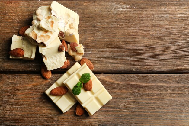 Pedaços de chocolate branco com nozes na cor de fundo de madeira