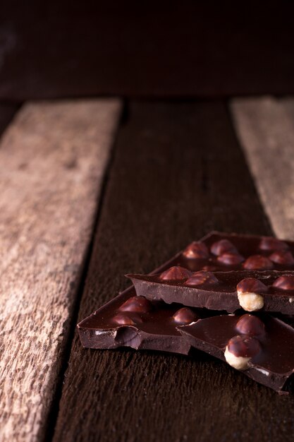 Foto pedaços de chocolate com avelãs em madeira.