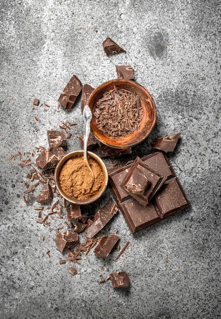 Pedaços de chocolate com cacau em pó na mesa rústica.