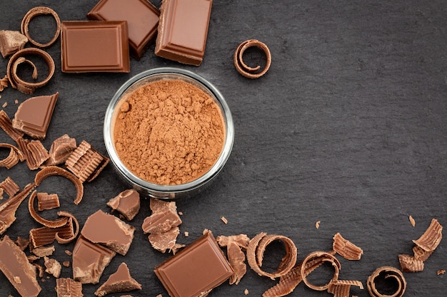 Pedaços de chocolate e cacau em pó no escuro.