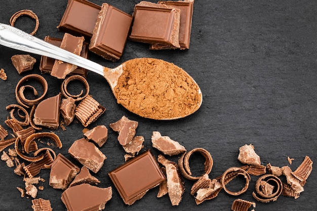 Pedaços de chocolate e cacau em pó no escuro.