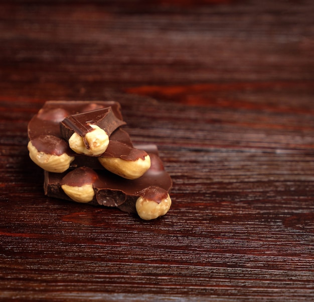 Foto pedaços de chocolate e nozes em uma mesa de madeira preta