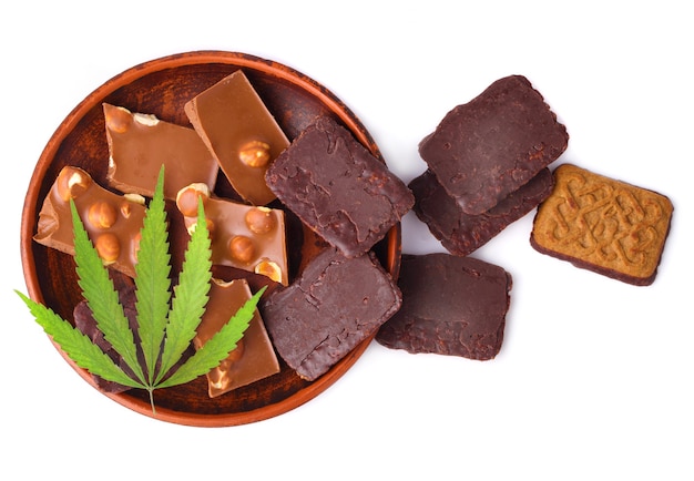 Pedaços de chocolate em um prato com folha de maconha ou cânhamo verde. postura plana. cookies retangulares de chocolate com cannabis cbd