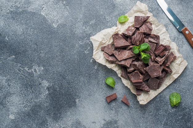 Pedaços de chocolate escuro esmagado com folhas de hortelã escuro texturizado com copyspace.