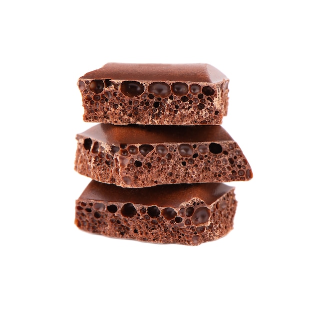 Pedaços de chocolate porosos isolados no fundo branco. Chocolate preto aerado.