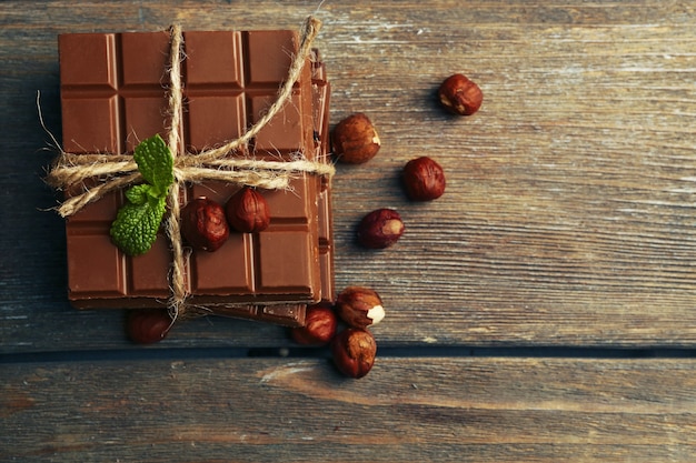 Pedaços de chocolate preto com nozes em fundo de madeira