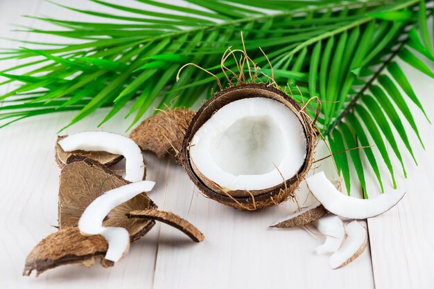 Pedaços de coco com um galho de palmeira em um fundo de madeira