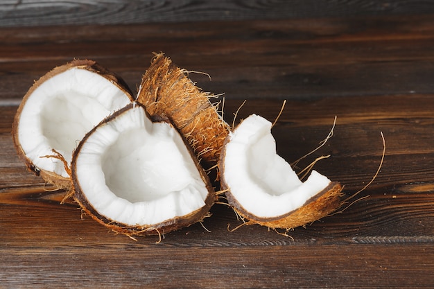 Pedaços de coco rachado no escuro de madeira