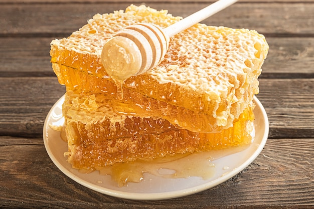 Pedaços de favo de mel em um prato e uma colher de mel