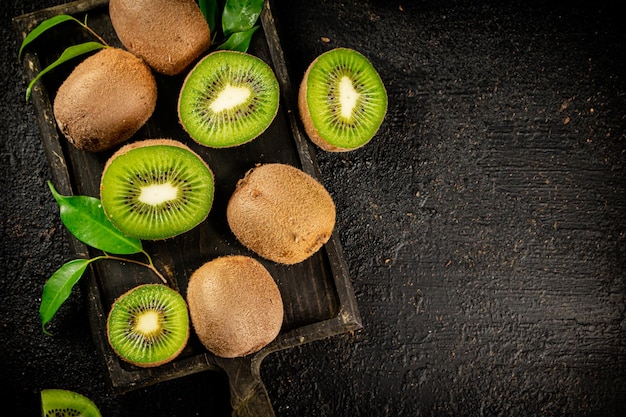 Pedaços de kiwi com folhas em uma placa de corte