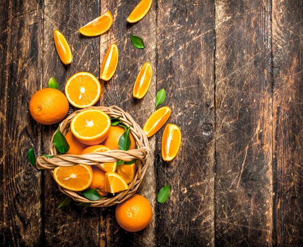 Pedaços de laranja fatiados na cesta. Em fundo de madeira.