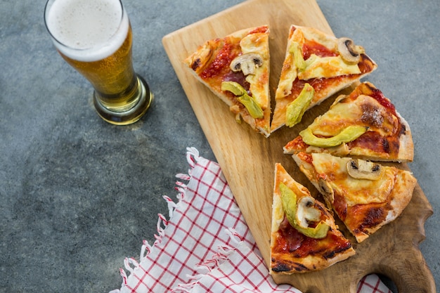 Pedaços de pizza italiana, servidos com copo de cerveja