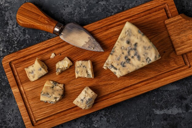 Pedaços de queijo azul na tábua de madeira.