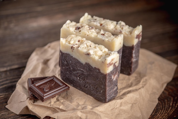 Pedaços de sabão de chocolate natural feito à mão em um invólucro de papel kraft em uma mesa de madeira