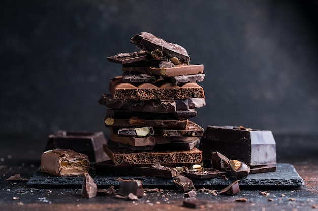 Pedaços de torre de barra de chocolate Pedaços escuros de avelã e amêndoa de chocolate quebrado Conceito de foto de comida doce