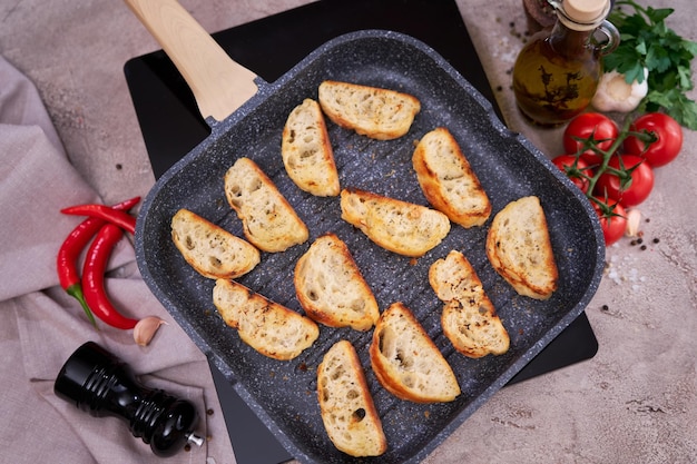 Pedaços fatiados de baguete na frigideira grill