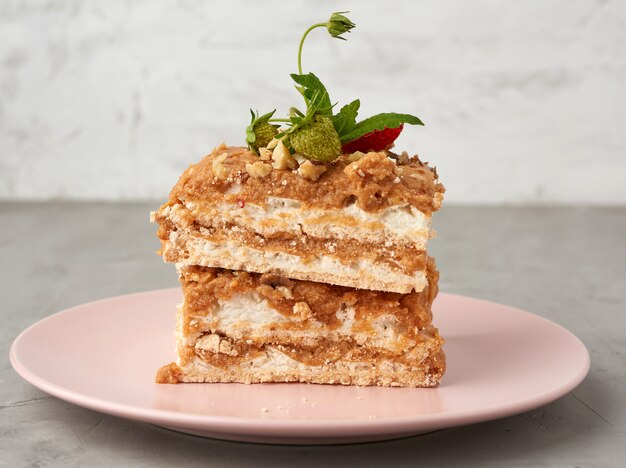 Pedaços quadrados de bolo de merengue com creme em um prato rosa