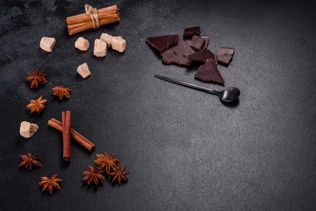 Pedaços quebrados de chocolate preto com anis estrelado e canela em fundo preto