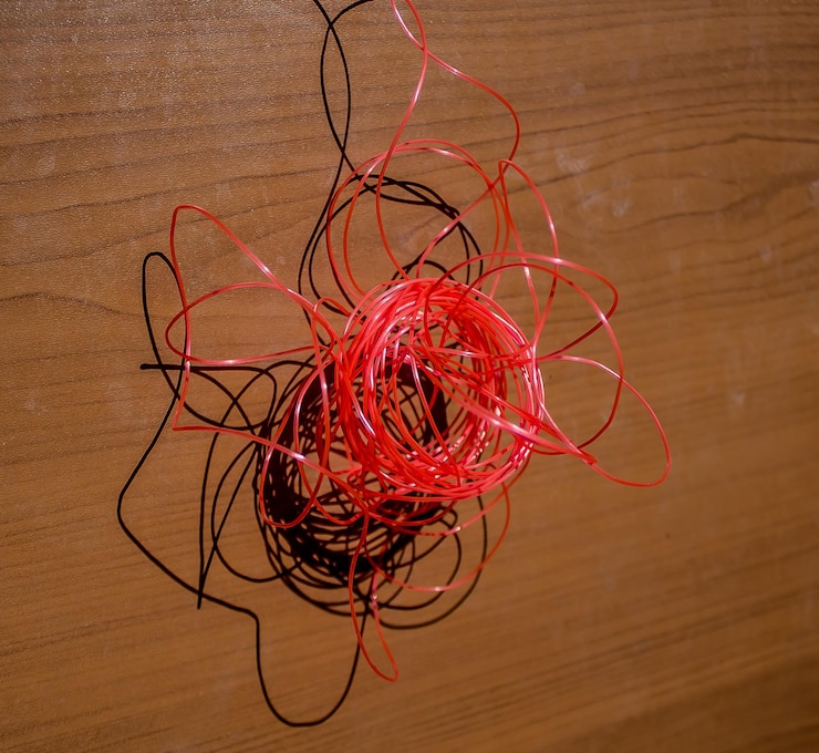 Foto un pedazo de alambre rojo está colocado en una superficie de madera