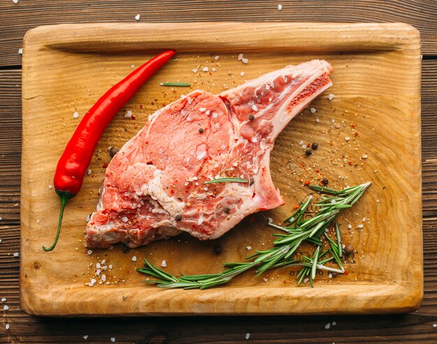 Pedazo de carne cruda en el condimento en la mesa de madera, vista superior