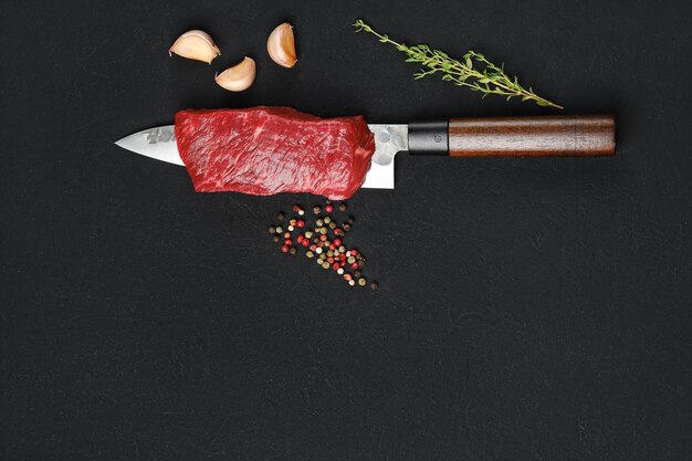 Foto un pedazo de carne de res jugosa cruda en la cuchilla del cuchillo