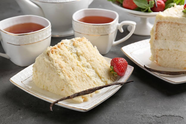 Pedazo de delicioso pastel de vainilla y tazas con té en la mesa