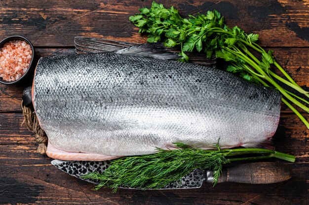 Pedazo grande de pescado salmón crudo cortado en una tabla de cortar de madera con cuchillo de chef