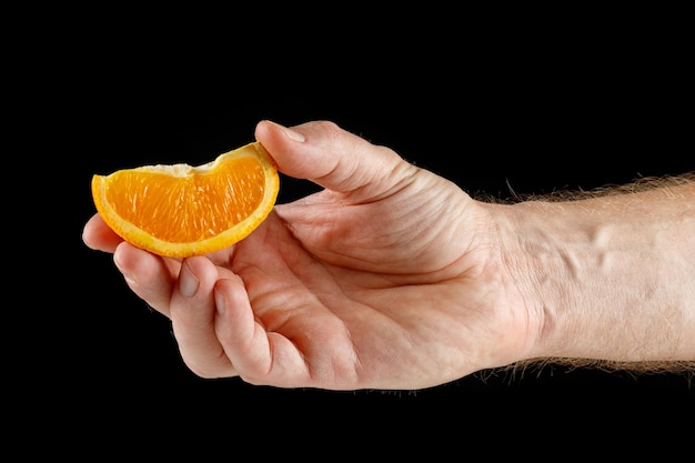 Pedazo de naranja en la mano aislado en negro