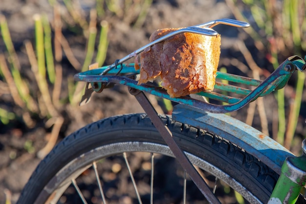 Pedazo de pan en el maletero de una bicicleta vieja comida y transporte pobreza y supervivencia en malas condiciones