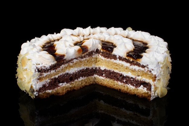 Pedazo de pastel blanco vertido con chocolate y decorado con crema de aceite sobre un fondo negro