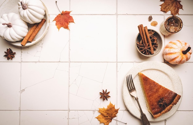 Pedazo de pastel de calabaza americano con canela en la vista superior de fondo de azulejo blanco