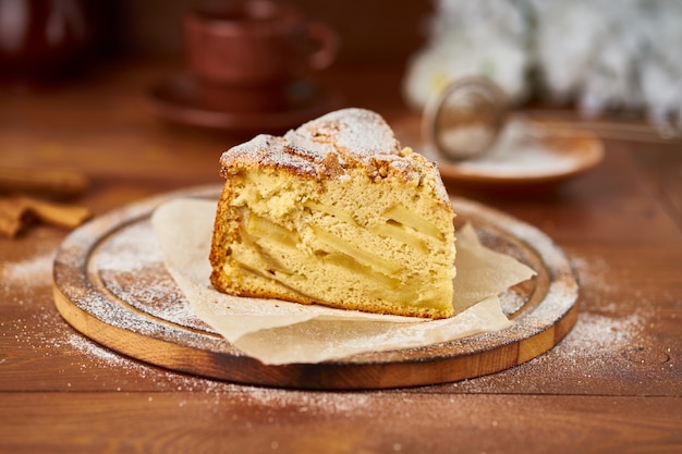 Pedazo de pastel francés de manzana con manzanas, canela en mesa de cocina de madera oscura