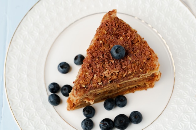 Pedazo de pastel de miel con nueces en la placa blanca.