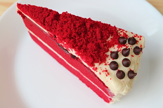 Pedazo de pastel de terciopelo rojo con queso crema en un plato blanco