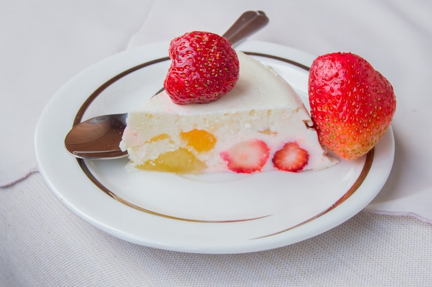 El pedazo de postre con fresas y crema en una cuchara de plato