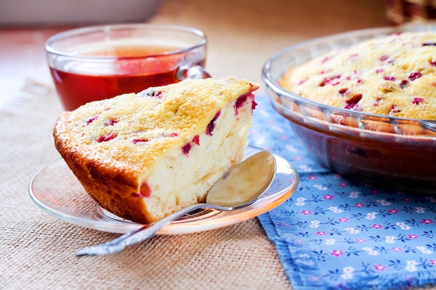 Pedazo de tarta de arándanos en placa de vidrio y taza de té