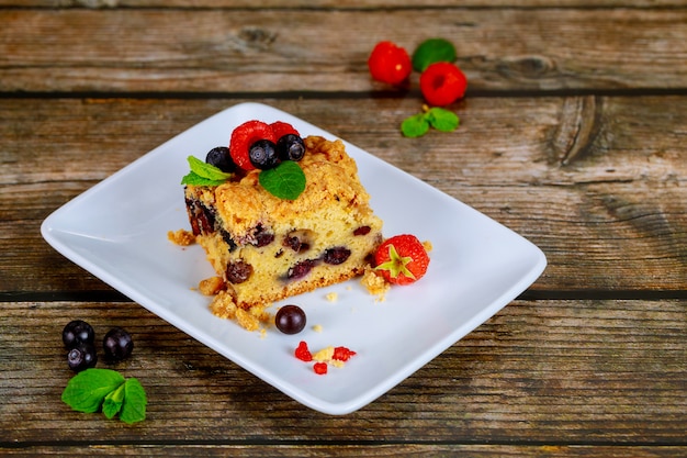 Pedazo de tarta casera de café de arándanos en un plato blanco sobre superficie de madera